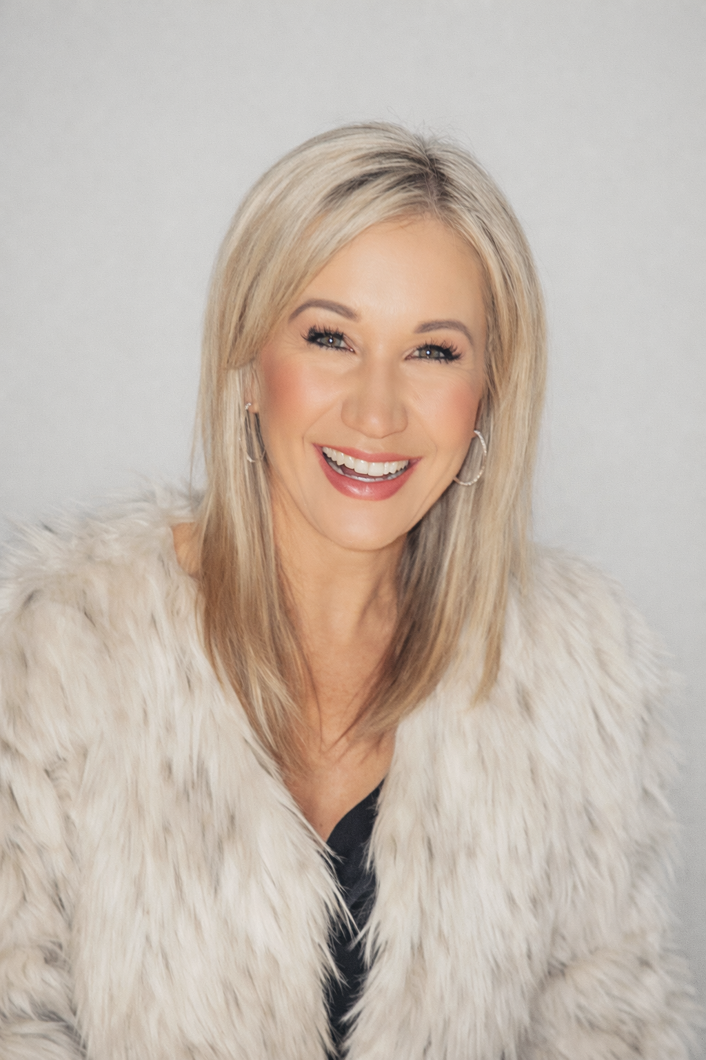 Janna laughing in a cream fur coat