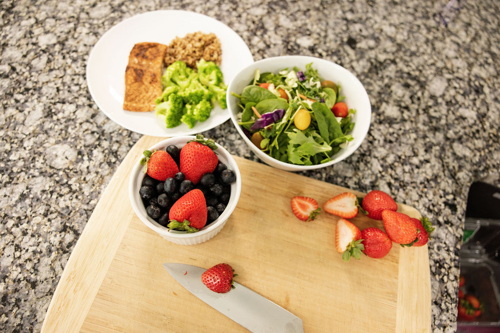 Plated meal with protein and grains, a salad bowl, and fresh berries on a countertop