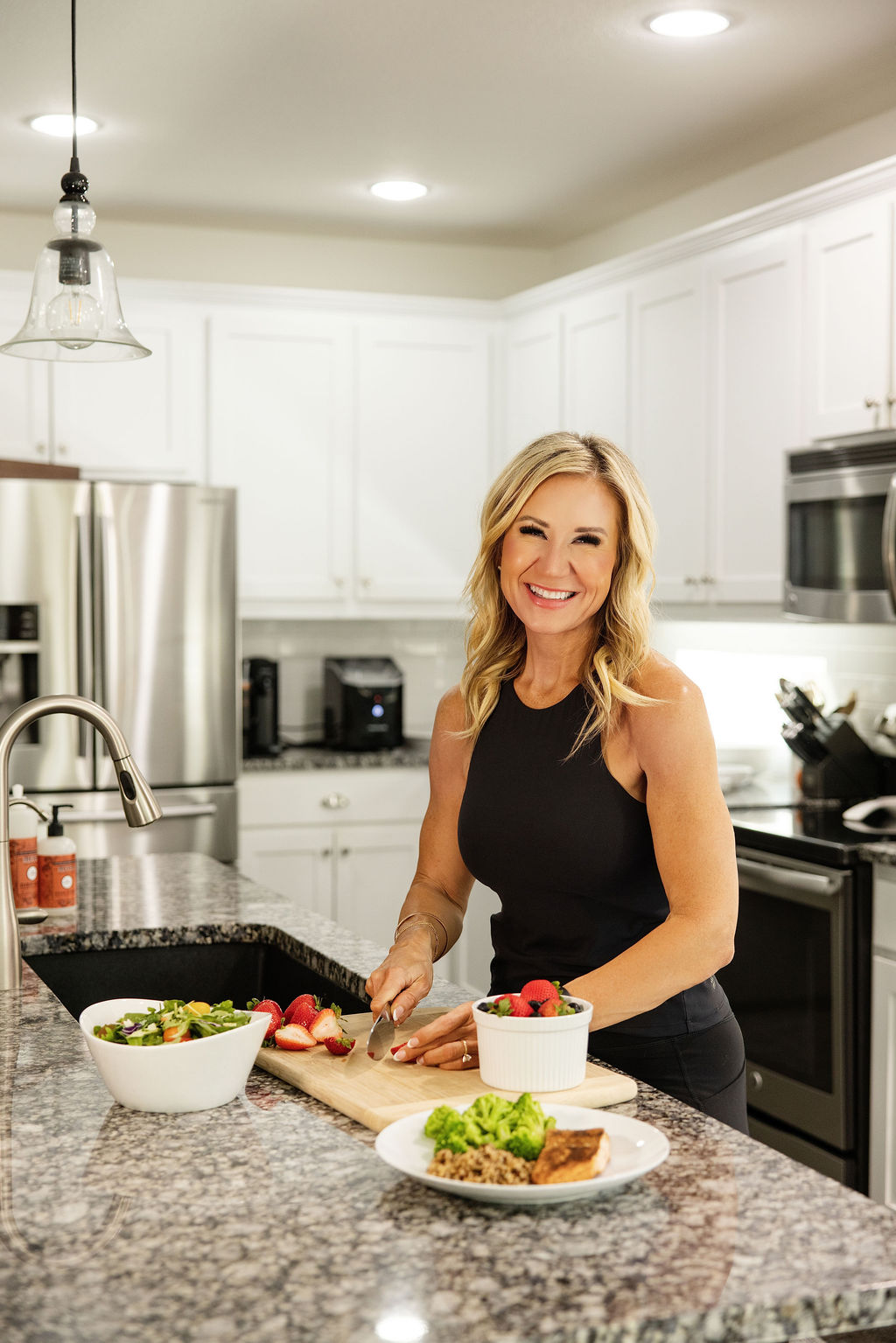 Janna Weaver slicing fresh strawberries in a kitchen with a prepared meal